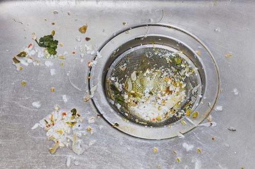 A kitchen sink drain catcher filled with food debris